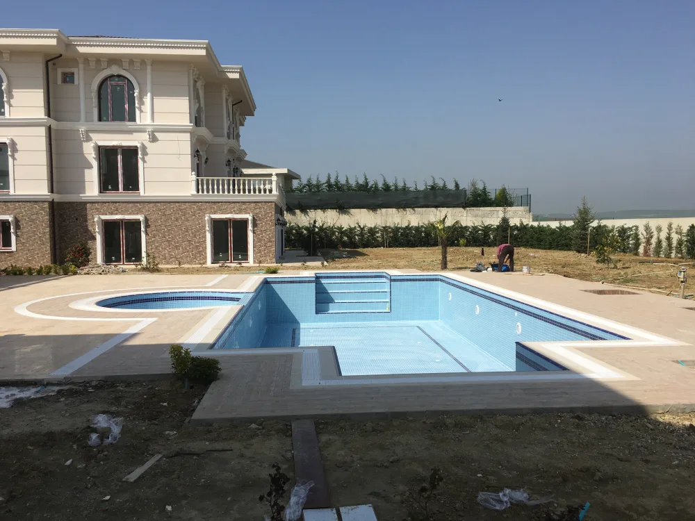 Müstakil bir evin bahçesinde yapımı süren, içi mavi fayanslı boş yüzme havuzu ve jakuzi bölümü.